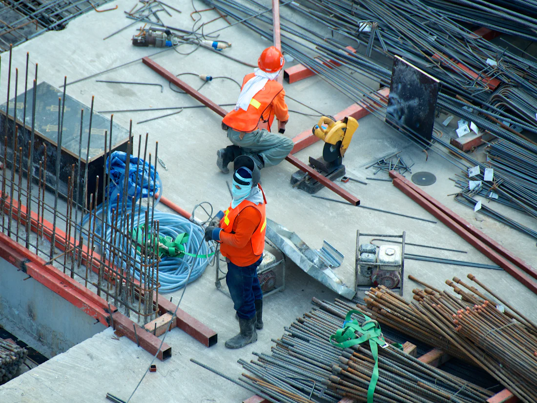 Trabajadores con casco y chaleco reflectivo en una obra de construcción